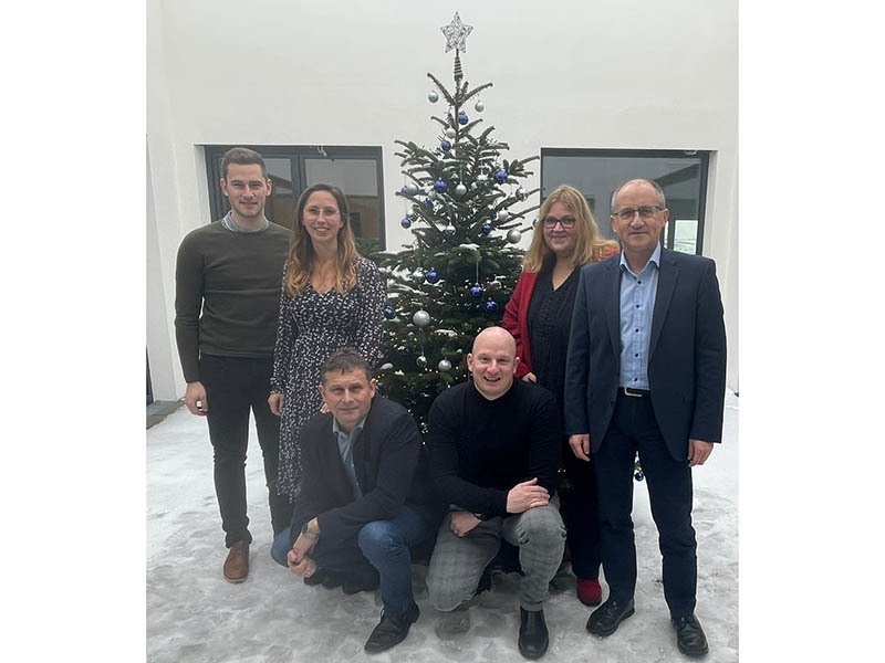Das Team der UNIQA GeneralAgentur Rahming im Büro vor einem Weihnachtsbaum.
